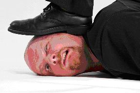 Man lying prone with a shoe stepping on the side of his face